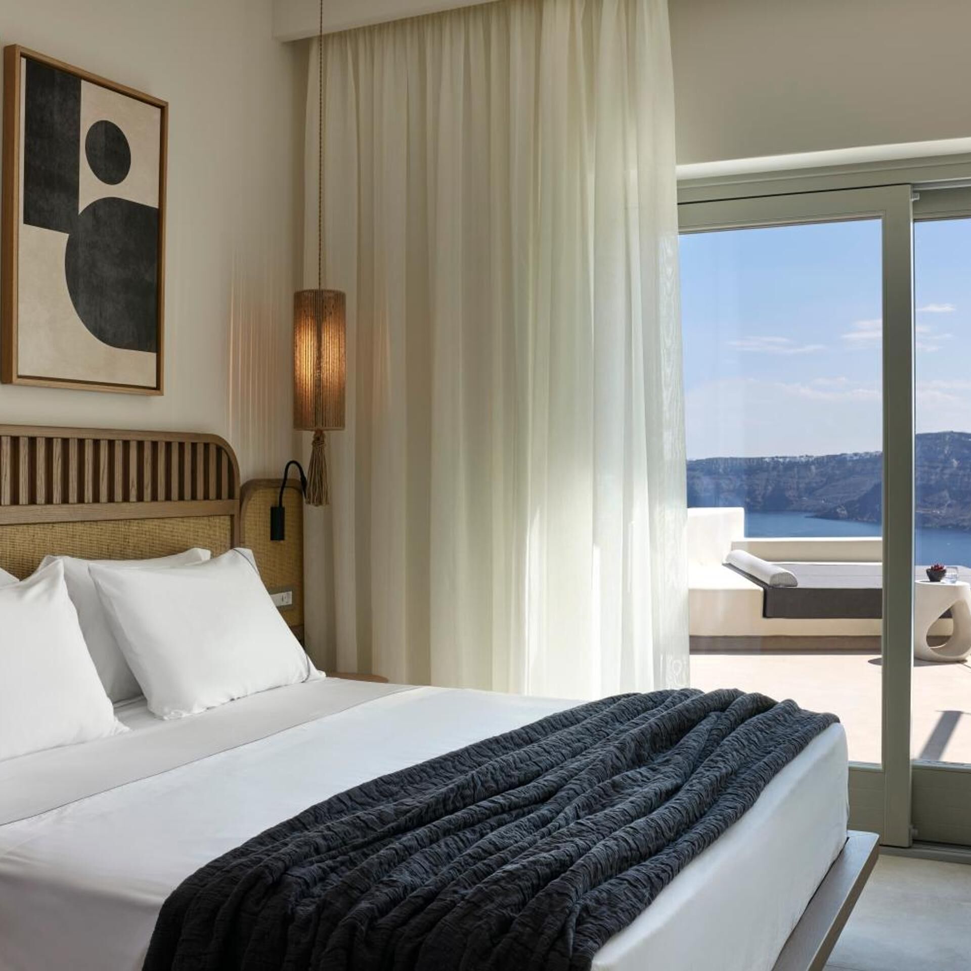 Quarto de hotel com uma cama, vista para o mar e um quadro na parede.