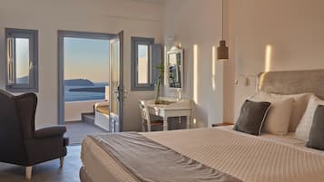 Un dormitorio con cama, una silla, un escritorio y vista al mar.