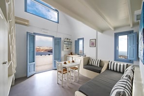 Ein Zimmer mit Esstisch, Stühlen, einer Couch und Blick durch offene Türen.