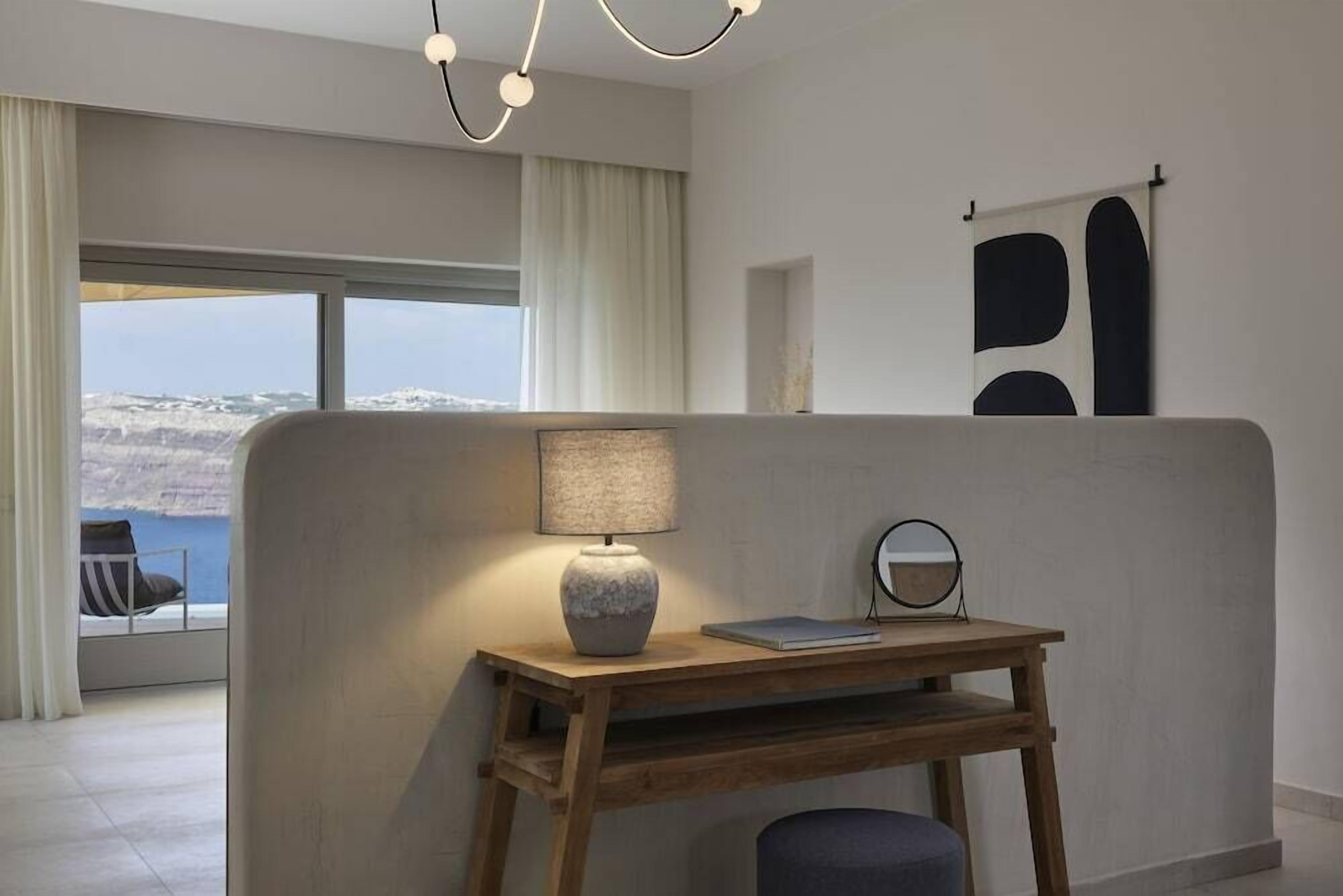 Quarto moderno com vista para uma paisagem nevada, uma escrivaninha de madeira com luminária, uma cadeira e um espelho redondo.
