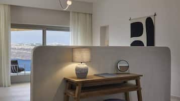 Quarto moderno com vista para uma paisagem nevada, uma escrivaninha de madeira com luminária, uma cadeira e um espelho redondo.