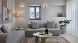A modern living room with a sofa, a round coffee table, and a lamp. - Apanemo Hotel and Suites (Santorini)