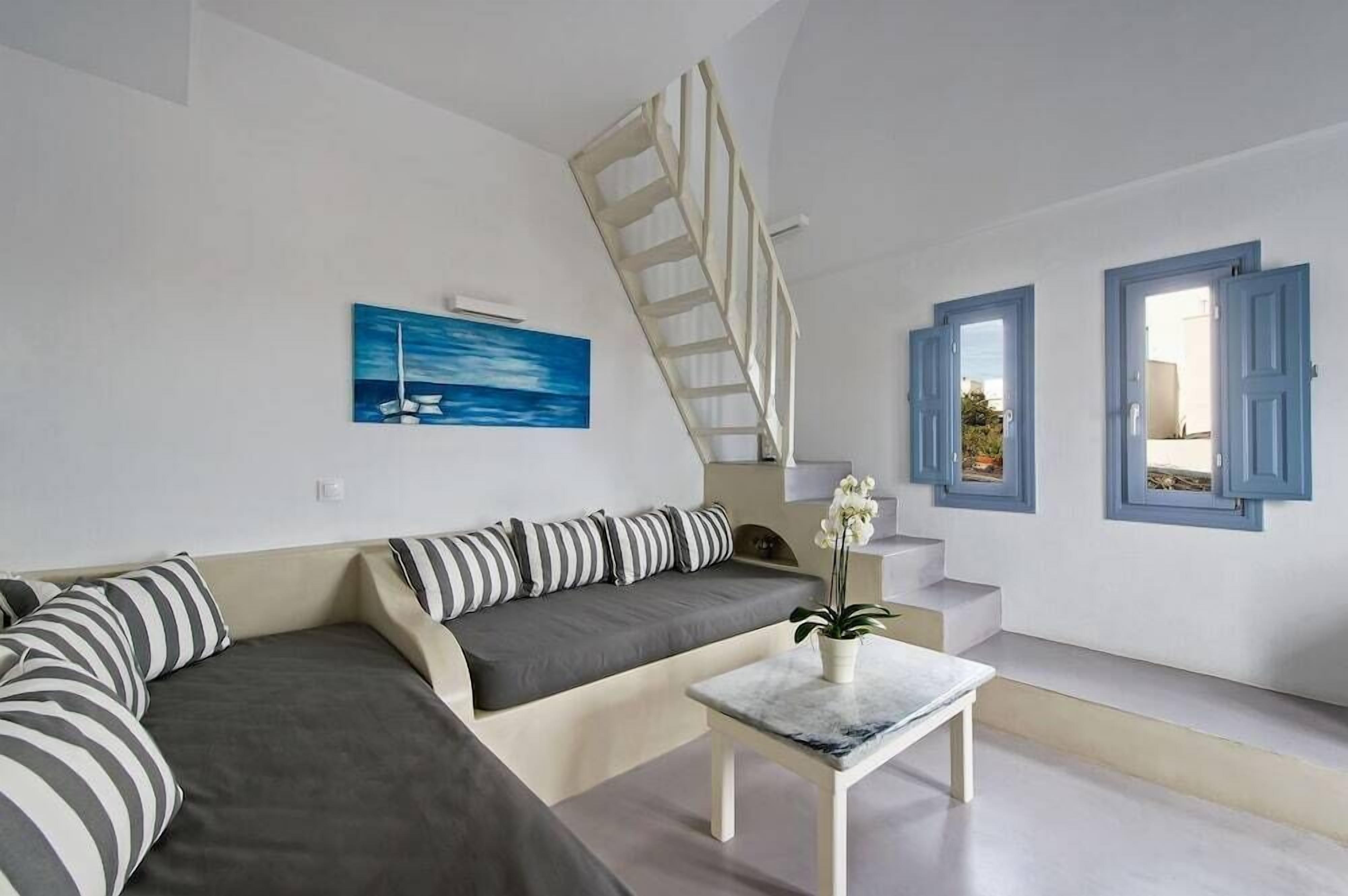 A modern living room with a sofa, a coffee table, a painting, and a staircase.