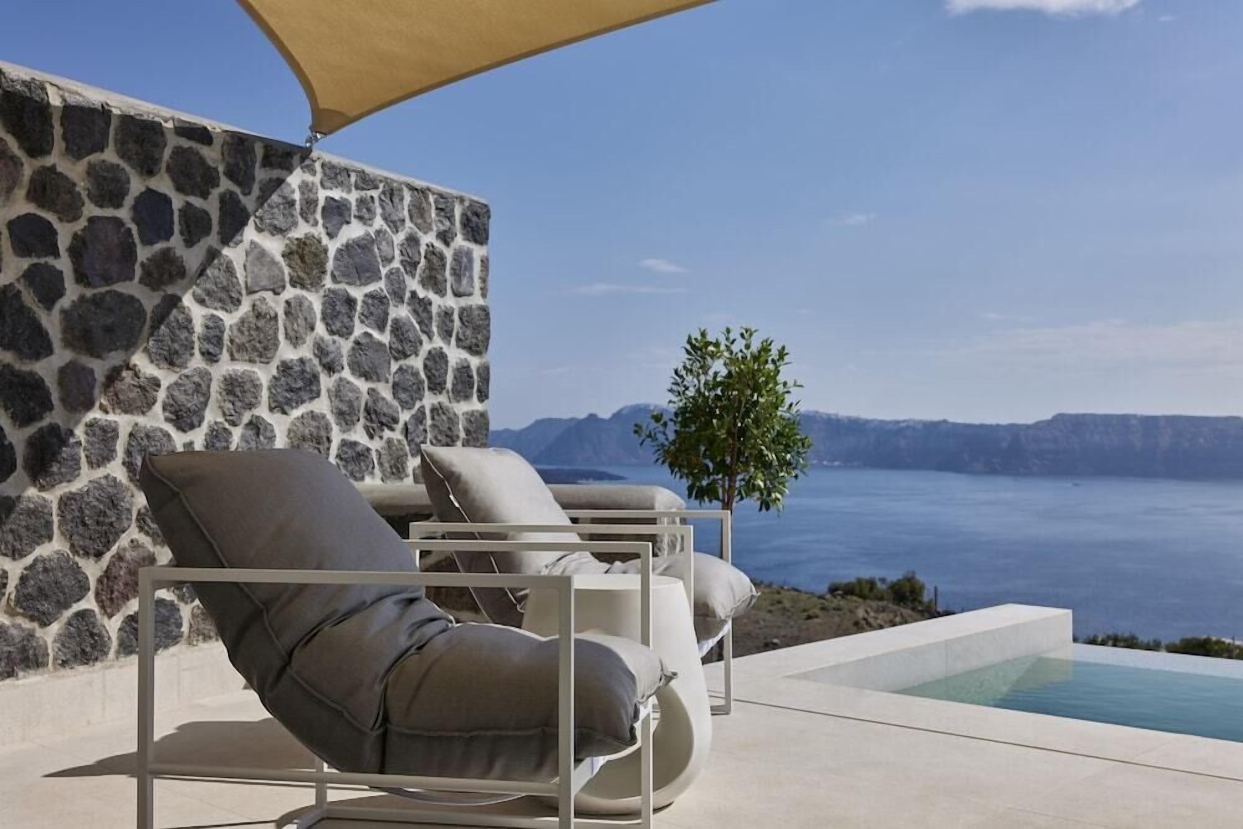 Un muro de piedra, una piscina y vista al mar.