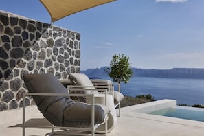 A stone wall, a pool, and a view of the sea.