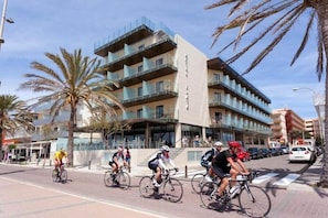 A multi-story building with balconies, a paved street, and palm trees. - Hotel Playa Mallorca (Palma de Mallorca)