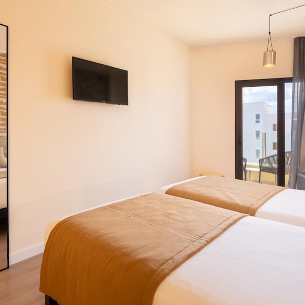 A hotel room with two beds, a flat-screen TV on the wall, and a view of the outside through a window. - Hotel Playa Mallorca (Palma de Mallorca)
