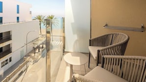 A balcony with a glass partition, a white refrigerator, wicker chairs, and a small round table. - Hotel Playa Mallorca (Palma de Mallorca)