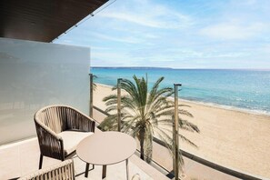 A balcony with a wicker chair and a small table, overlooking a beach with palm trees and the sea. - Hotel Playa Mallorca (Palma de Mallorca)