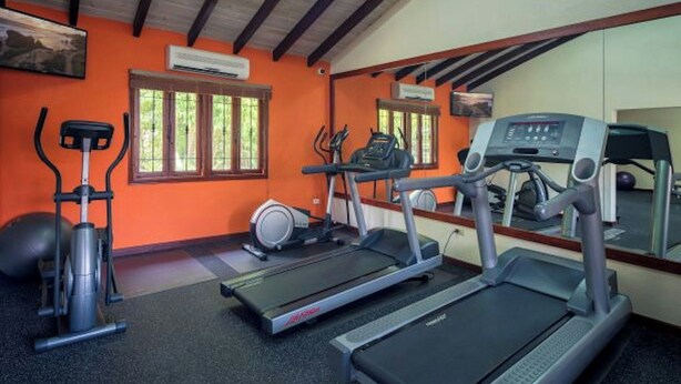 A gym with treadmills, an elliptical, and a stationary bike. - Sugar Cane Club Hotel & Spa (Speightstown)