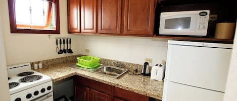 A kitchen with wooden cabinets, a microwave, a stove, and a sink.