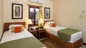 A hotel room with two beds, a desk, a telephone, and an air conditioning unit. - Sugar Cane Club Hotel & Spa (Speightstown)