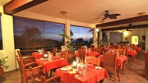 An outdoor dining area with multiple tables and chairs, covered by a roof, and equipped with table settings. - Sugar Cane Club Hotel & Spa (Speightstown)