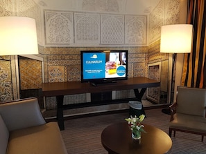 A hotel room with a television displaying 'Culinarium' and a table with a vase of flowers. - Hotel Tui Blue Oceana Suites (Hammamet)