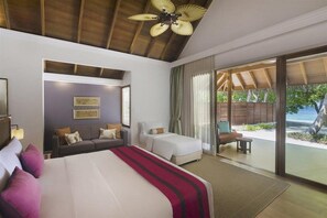Habitación de hotel con una cama grande, un sofá, un escritorio y vista a la playa.