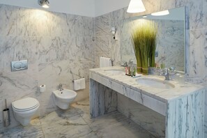 Une salle de bain avec un lavabo en marbre, un bidet et des toilettes.