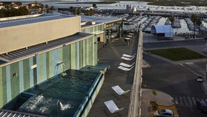 A rooftop pool with lounge chairs and a view of a marina with boats. - Hotel Faro and Beach Club (Faro)