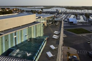 A rooftop pool with lounge chairs and a view of a marina with boats. - Hotel Faro and Beach Club (Faro)