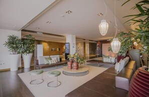 Un hall d’entrée moderne avec un espace salon, de grandes plantes en pot et des luminaires suspendus.