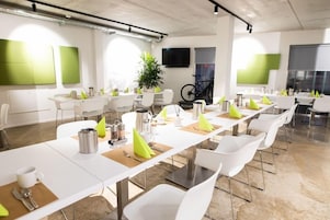 Uma sala de conferência moderna com mesas e cadeiras brancas e detalhes em verde.