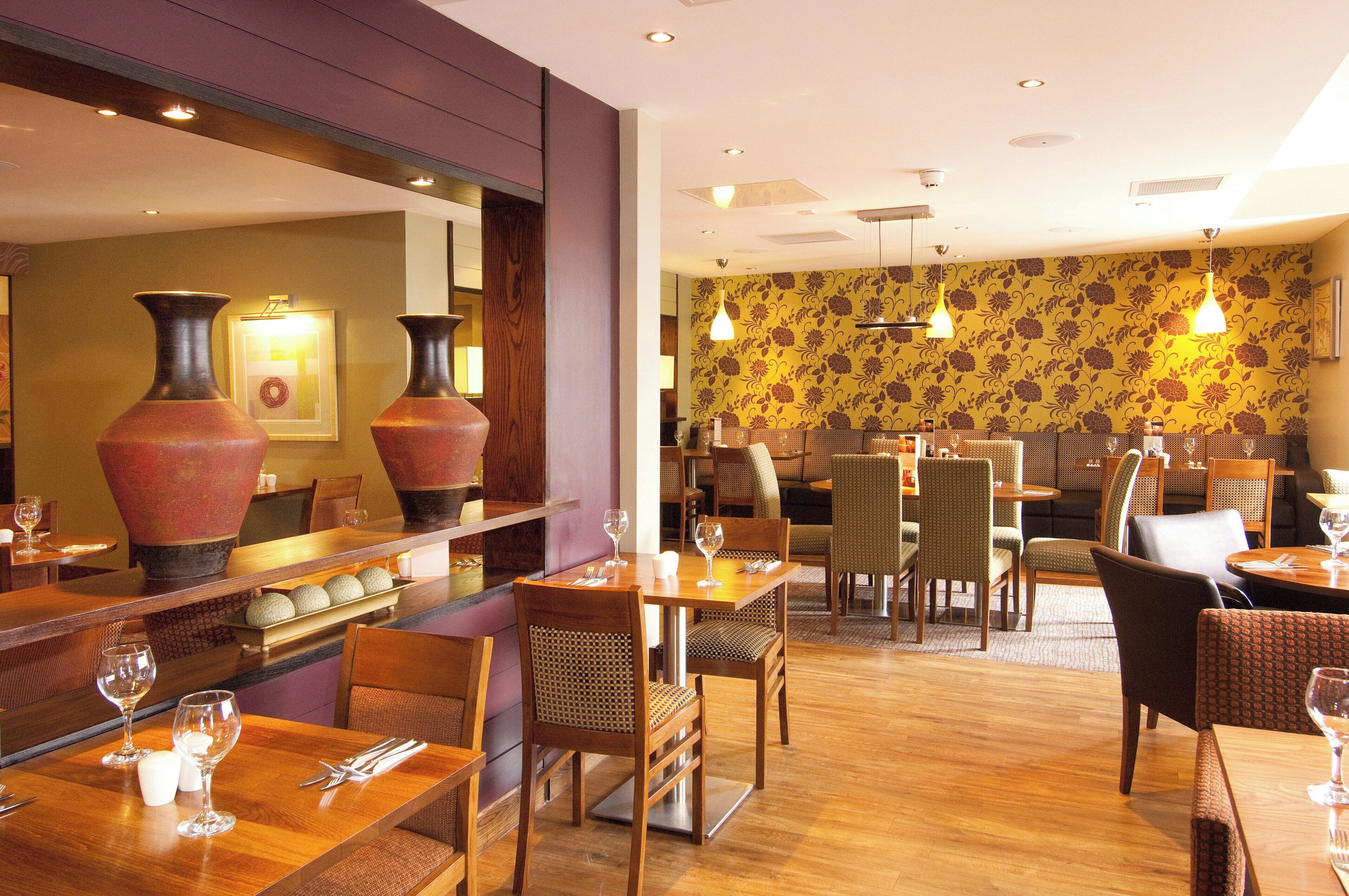 Ein Restaurantinneres mit Holztischen, -stühlen und einer Bar.
