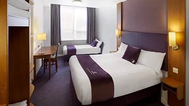 A hotel room with a large bed, a desk, and a chair. - Premier Inn Sunbury (Sunbury on Thames)