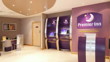 A Premier Inn reception area with check-in kiosks and a private room door.