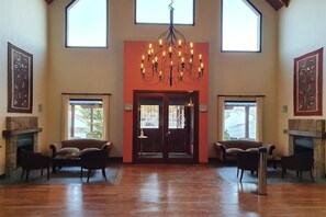 A spacious lobby with a grand chandelier, two fireplaces, and large windows. - Xelena Hotel and Suites (El Calafate)