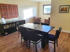 A dining area with a table and chairs, a bookshelf, and a window with a view. - Xelena Hotel and Suites (El Calafate)