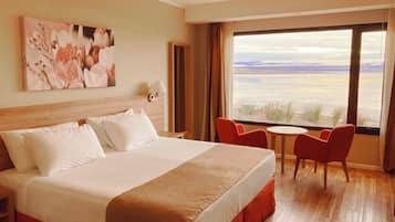Ein Hotelzimmer mit einem großen Bett, einem Schreibtisch, zwei Stühlen und einem großen Fenster mit Blick.