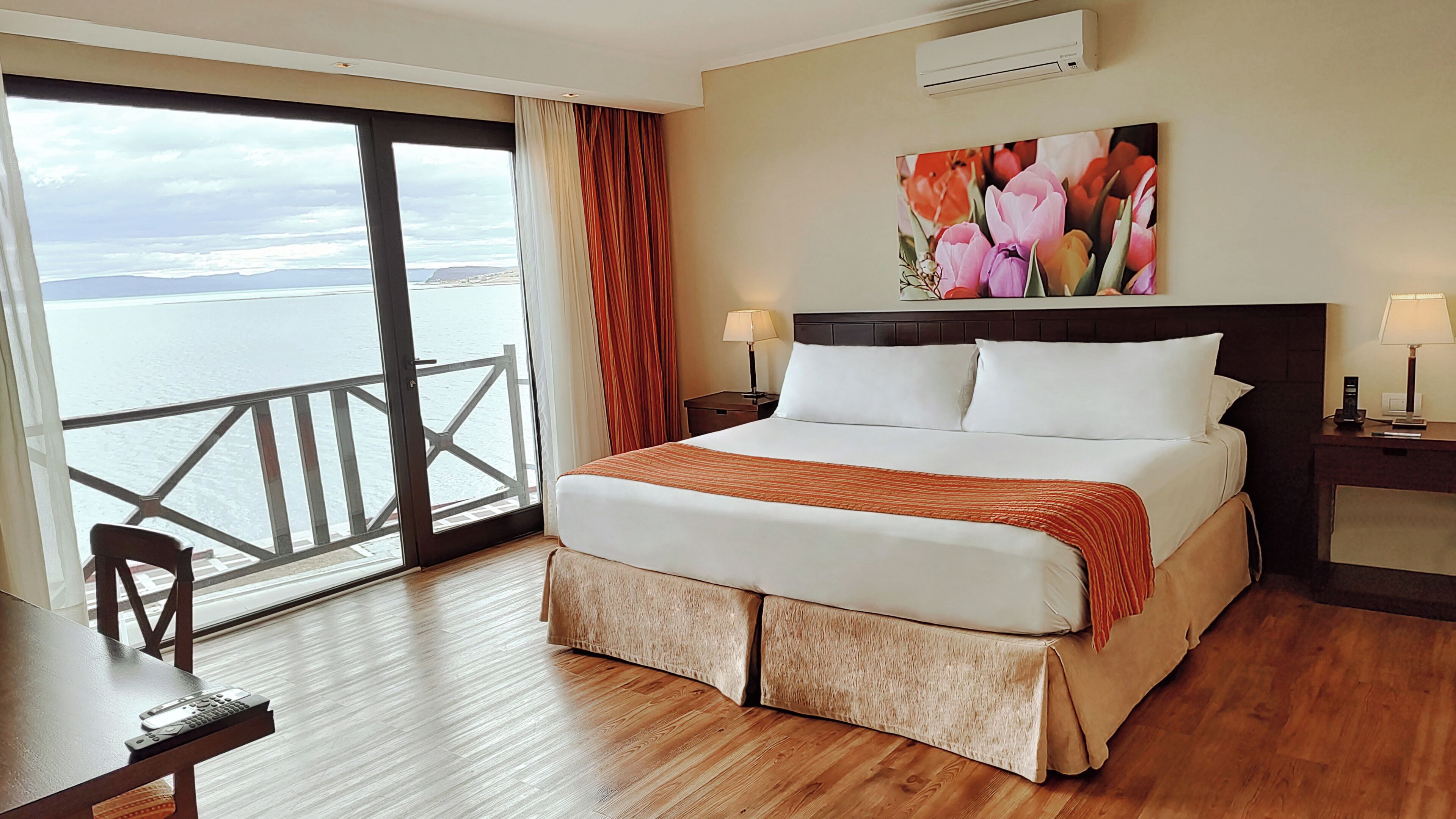 Habitación de hotel con una cama grande, vista al mar, un cuadro en la pared y un balcón.
