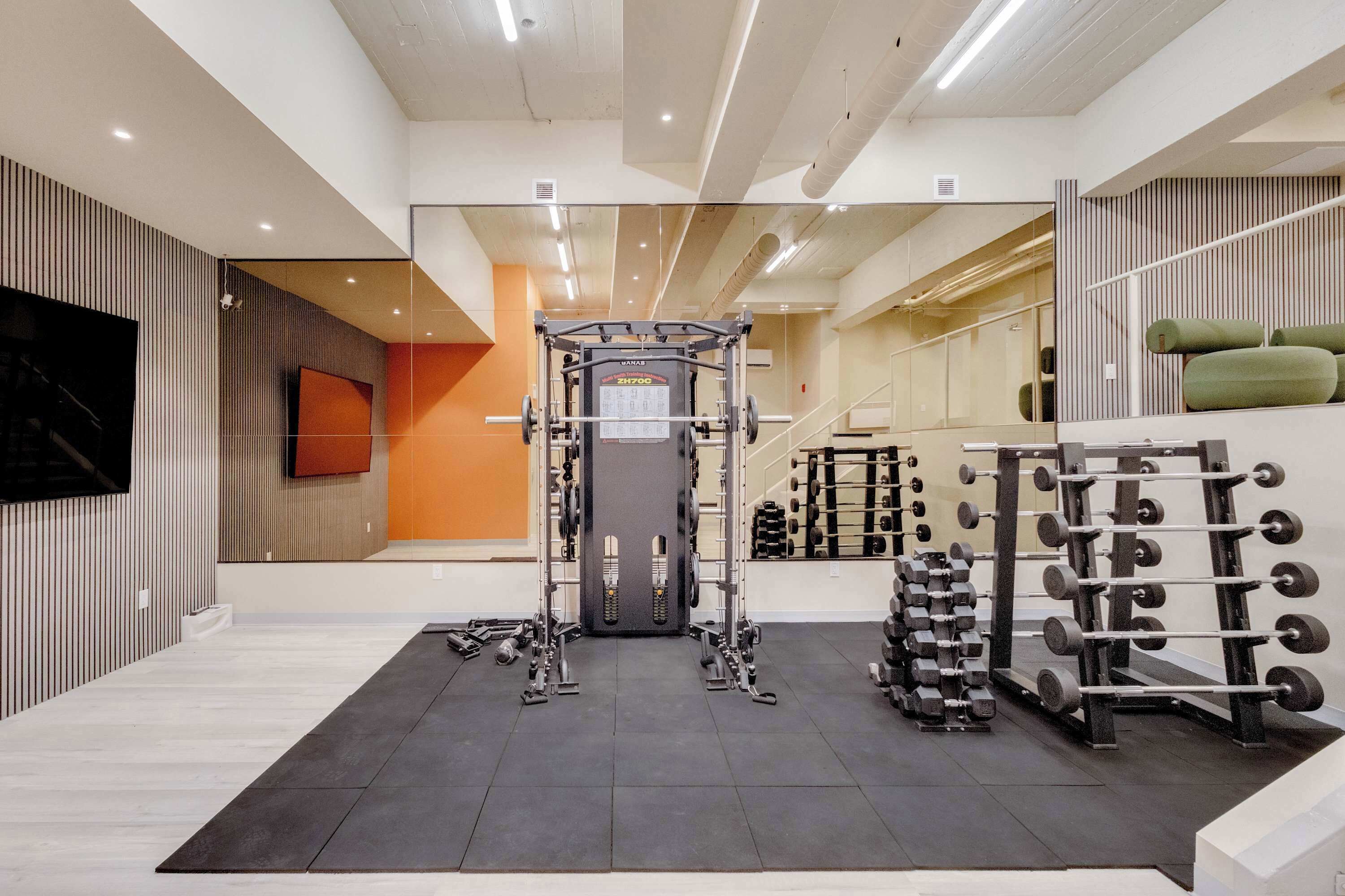A gym with a squat rack, weight bench, and various dumbbells.