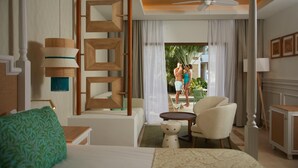 Quarto de hotel com uma cama, uma cadeira, uma pequena mesa, um ventilador de teto e vista para o exterior.