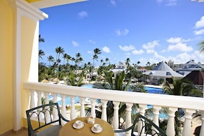 Uma varanda com vista para um resort, incluindo piscina e palmeiras.