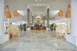 A spacious lobby with a reception desk, wicker chairs, and a marble floor. - Bahia Principe Explore Esmeralda (Punta Cana)