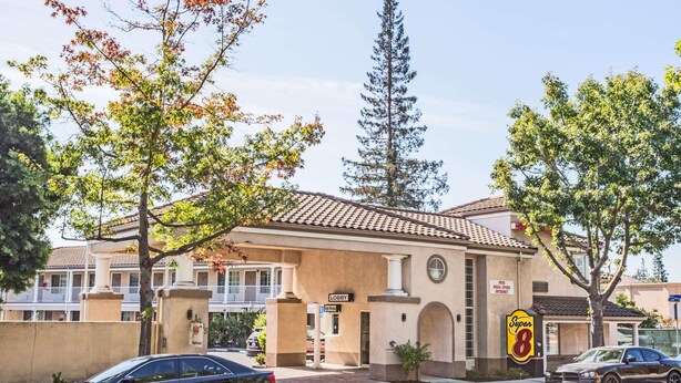 A hotel with a beige facade, a sign indicating 'Free High-Speed Internet', and a 'Right Window' sign. - Super 8 by Wyndham Mountain View (Mountain View)