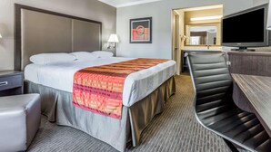 A hotel room with a bed, a desk with a flat-screen TV, a chair, and a bedside table. - Super 8 by Wyndham Mountain View (Mountain View)