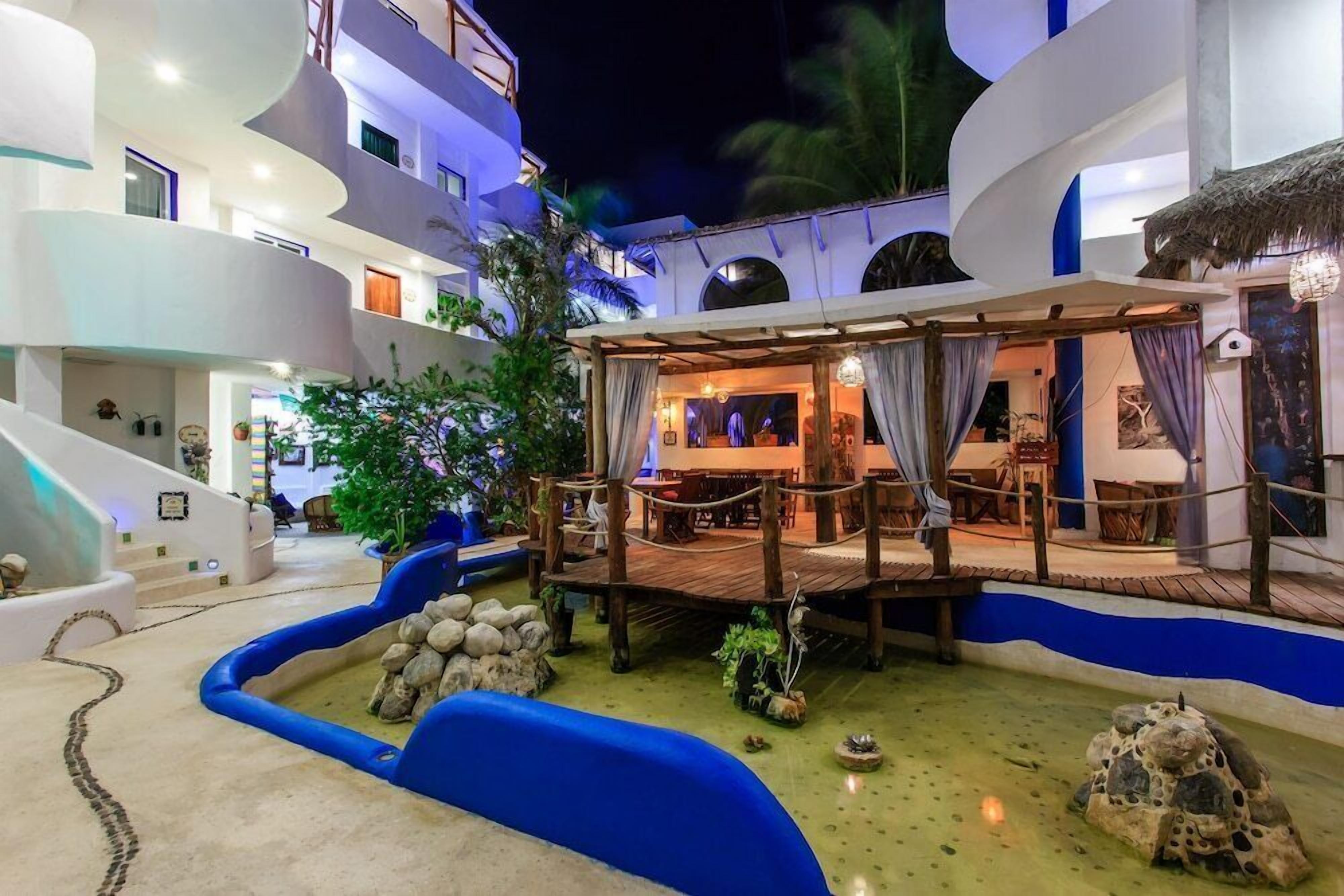 A multi-level hotel with a pool area, outdoor seating, and a covered dining area.