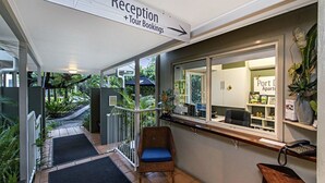 Un espace d’accueil avec un panneau indiquant où réserver des visites guidées, un comptoir d’accueil, une chaise et une vue sur un appartement situé dans le port.