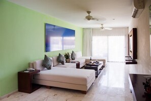 A hotel room with a large bed, a sofa, a coffee table, and a TV. - The Palm at Playa (Playa del Carmen)