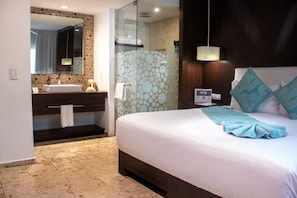 A hotel room with a bed, a bathroom with a sink, and a shower area. - The Palm at Playa (Playa del Carmen)