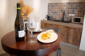 Una mesa de comedor con una botella de vino, una copa de vino y un plato de pasteles.