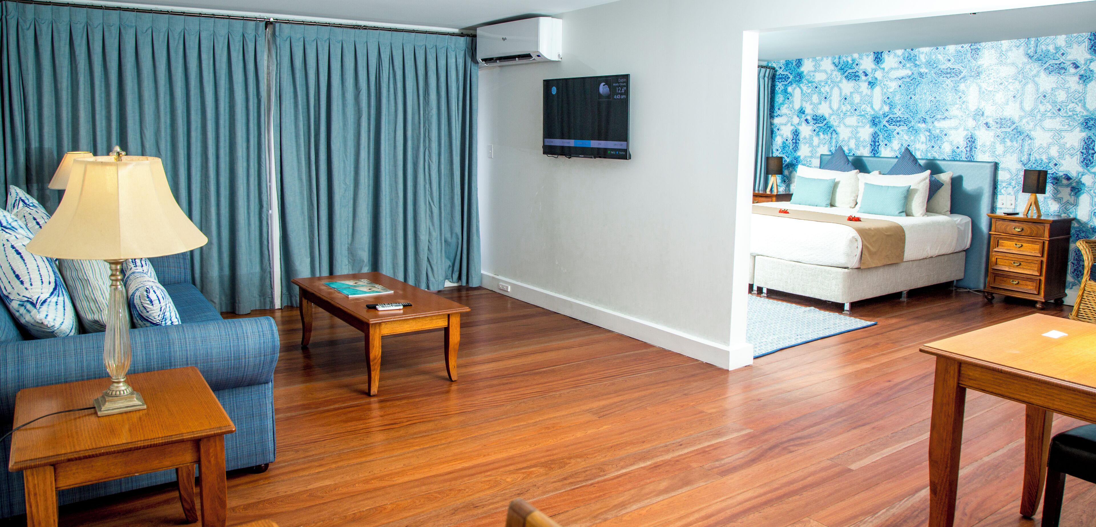Una sala de estar moderna con un sofá, una mesa de centro y un televisor montado en la pared.
