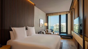 A hotel room with a large bed, a seating area with a sofa and armchairs, a TV, and a large window offering a city view. - Banyan Tree Dubai (Dubai)