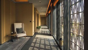 A corridor with a seating area, a potted plant, and a patterned window. - Banyan Tree Dubai (Dubai)