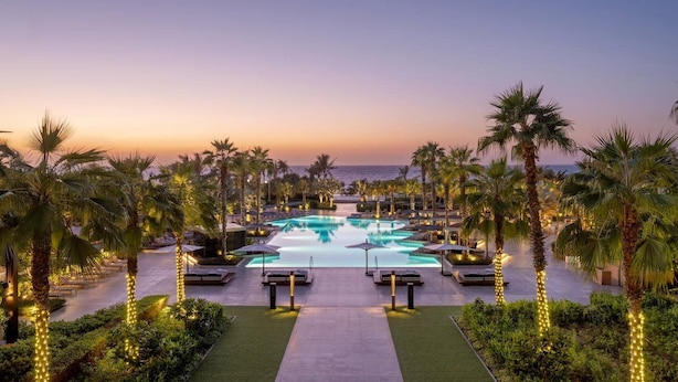 A resort pool area with palm trees and lounge chairs. - Banyan Tree Dubai (Dubai)