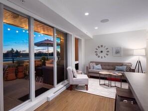 A modern living room with a large sliding glass door leading to an outdoor patio area. - City Oasis - 1br - Furnished 1BR + Parking (Vancouver)
