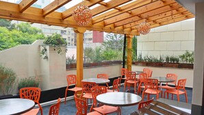 An outdoor seating area with wooden beams and orange chairs. - Senia Reforma (Mexico City)