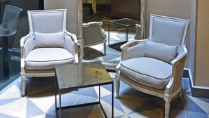 A lobby with two armchairs, a glass coffee table, and a decorative hanging light fixture. - Senia Reforma (Mexico City)