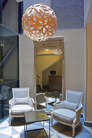Una hall con due poltrone, un tavolino in vetro e un lampadario decorativo.